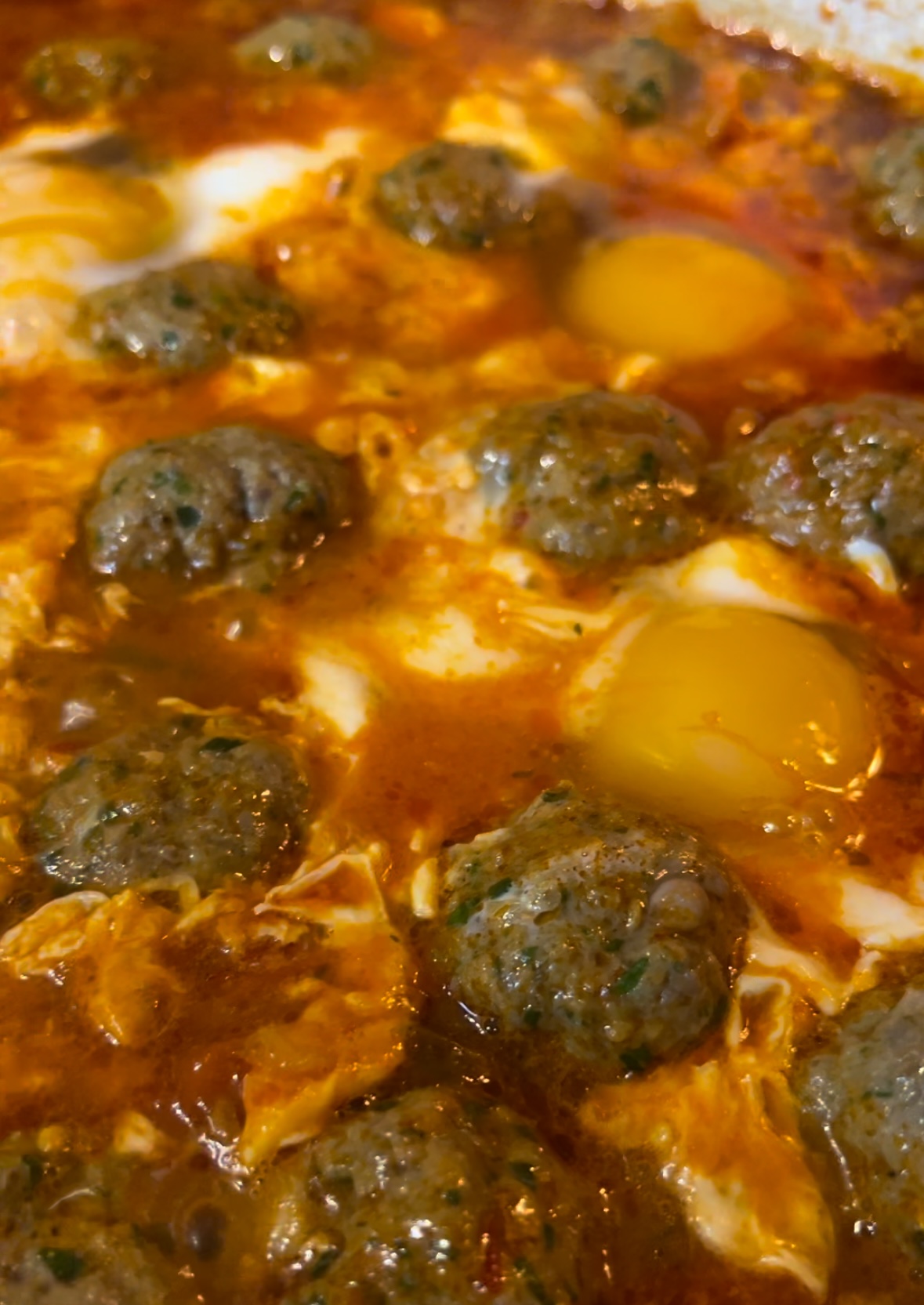 raw eggs in between kefta meatballs and tomato sauce